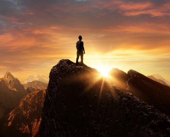 Man standing on mountain looking at sunrise